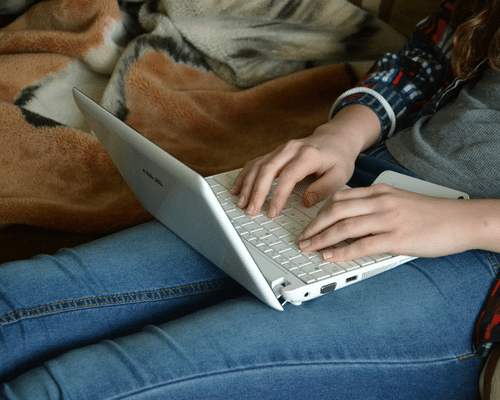 teen typing on a laptop